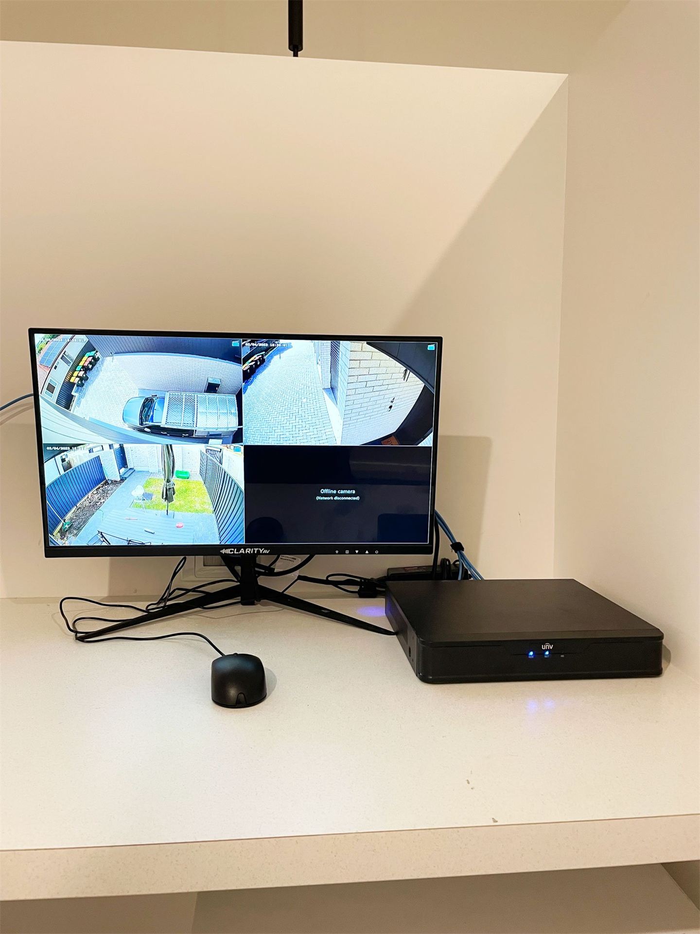 Monitor showing four security camera views beside a new recorder