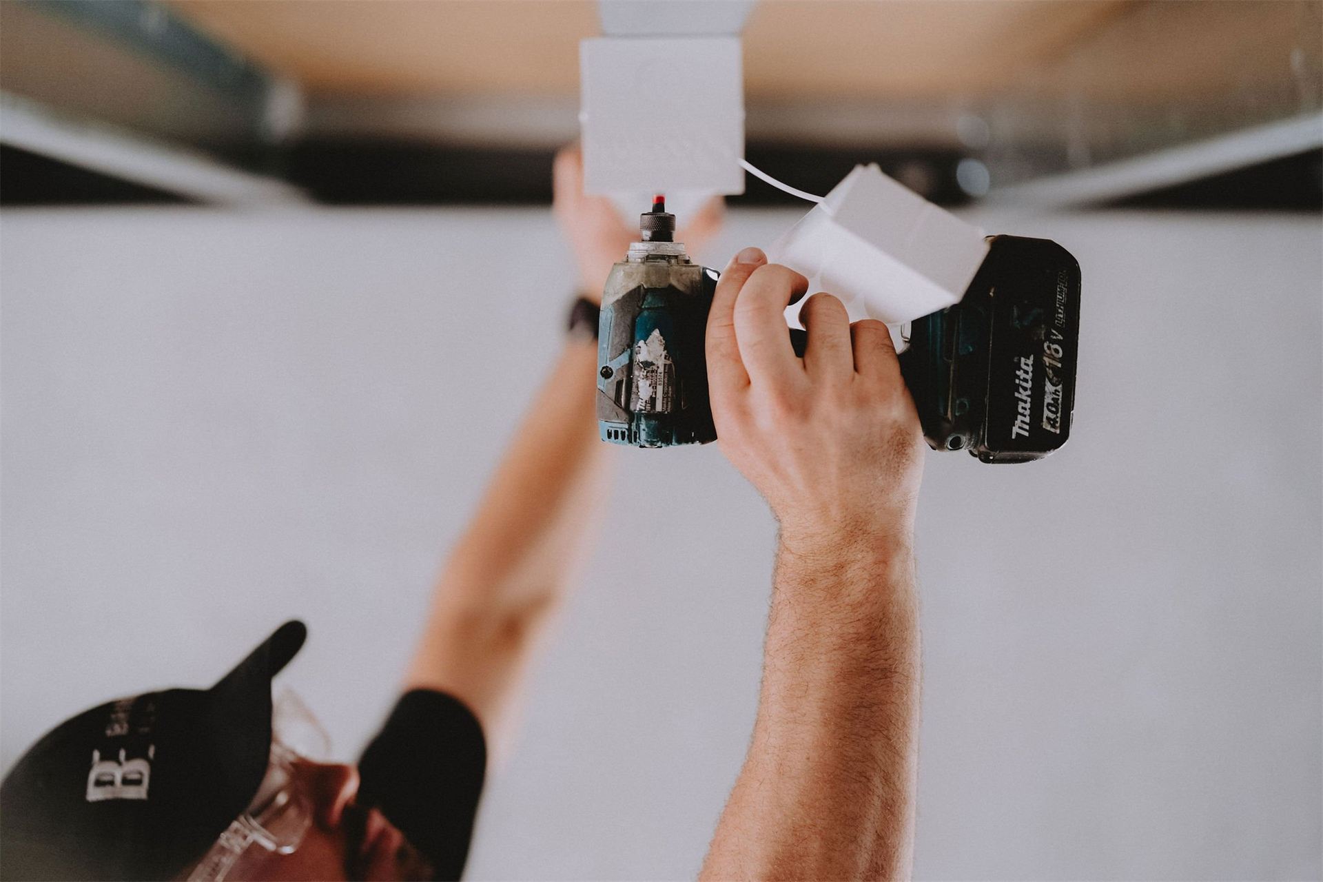 Electrician drilling into a ceiling during electrical work