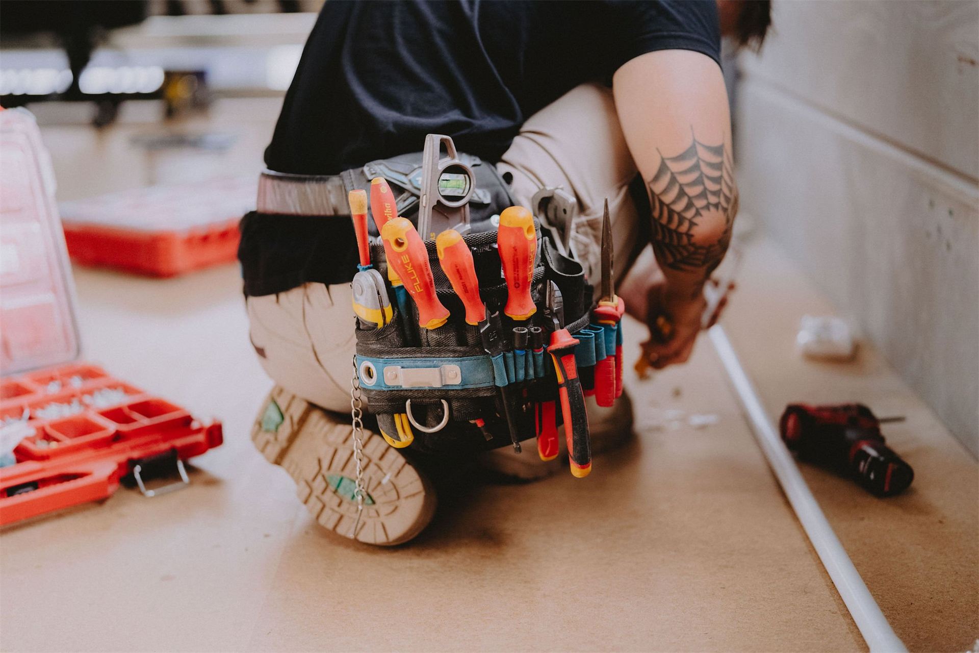 Electrician kneeling on site wearing a full tool belt