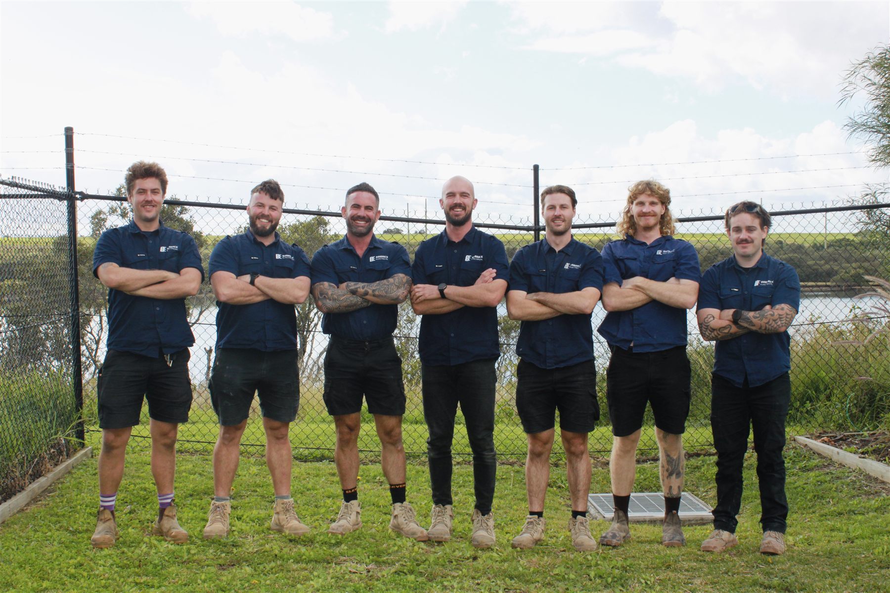 The Barrack Electrical team in uniform, standing together by the water